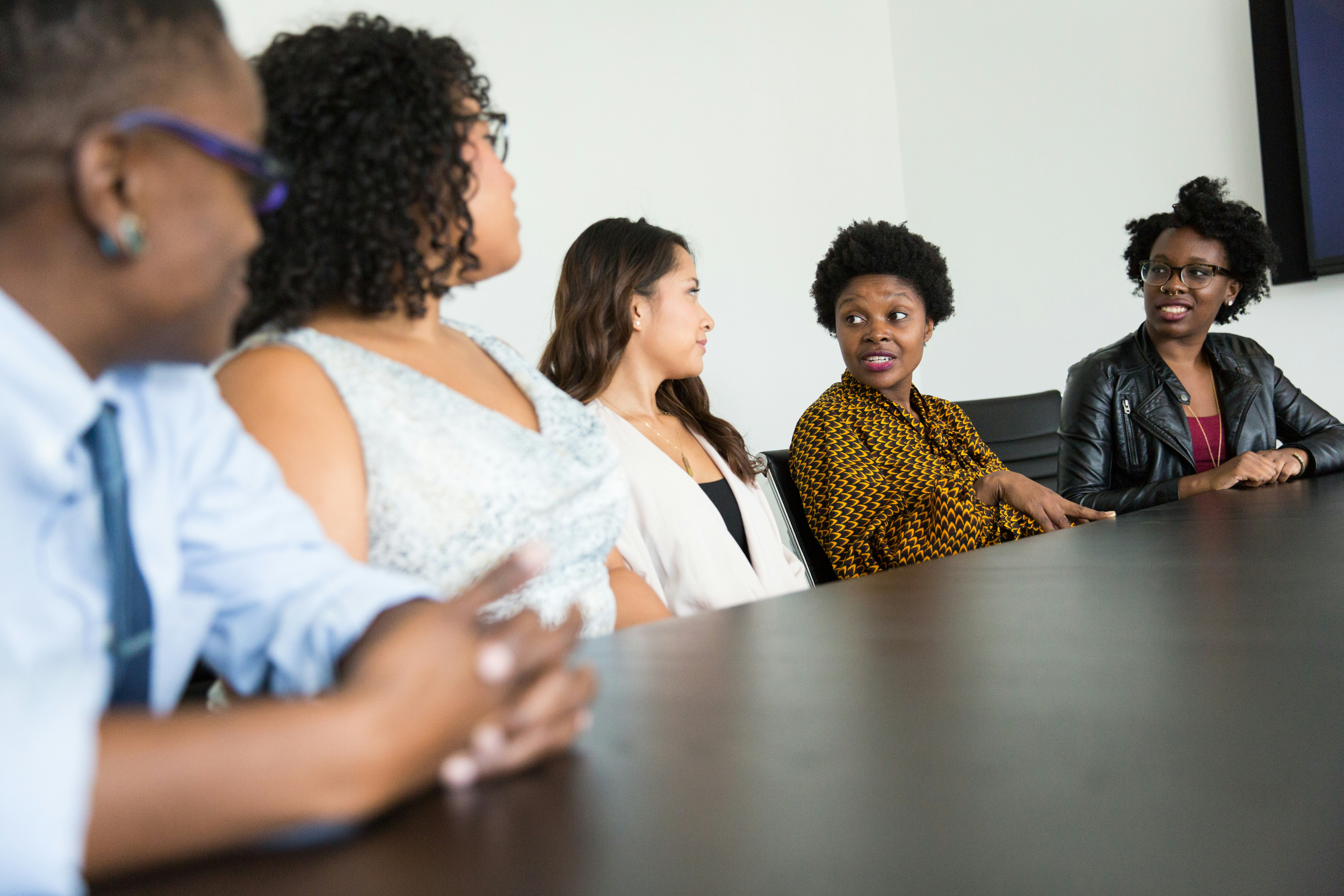 Women entrepreneurs of color talk around a conference table in a bright meeting room, the kind of founders a new GEM report finds start strong but stall at scale