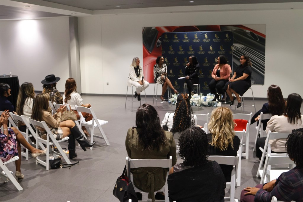 Guests listen to The Legacy League Women's Legal Playbook panel inside the Porsche Chantilly showroom
