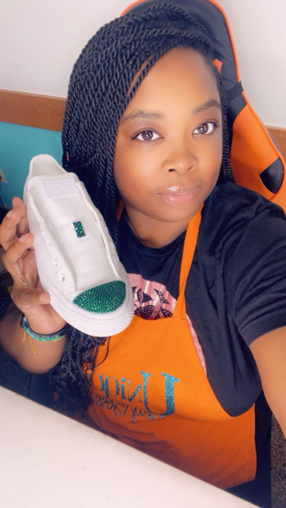 Jillian Lee, founder of UniqueLee Creations, holding a custom rhinestone sneaker in her studio