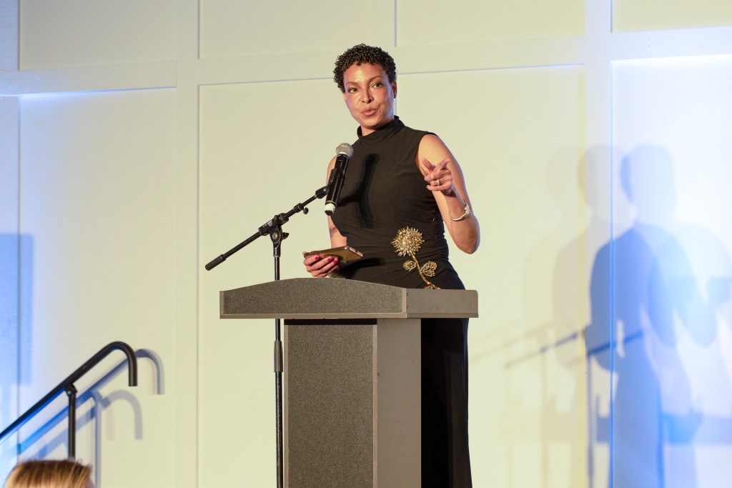 Dr. Shawna Aarons-Cooke speaking at a podium at the 2025 Norman Vincent Peale Awards Benefit